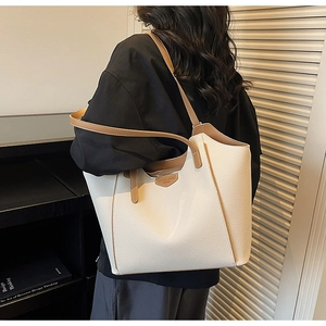 Detail view of large white lychee leather tote bag with brown straps and gold logo