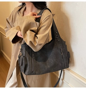 Detail of dark gray matte leather tote bag featuring functional side pockets and wide strap
