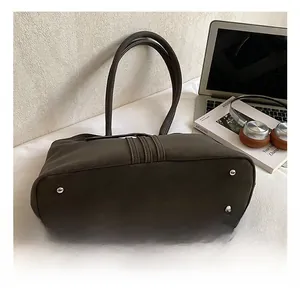 Detailed view of dark brown leather tote bag with silver protective bottom rivets
