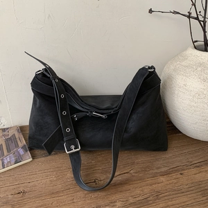 Detail of black matte leather tote bag with wide strap and silver metal eyelets