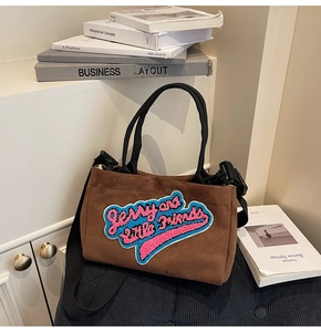 Détail du sac cabas en peluche marron avec broderie et bandoulière noire réglable