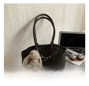 Detailed view of a dark brown retro tote bag with a plush bunny charm and top handles
