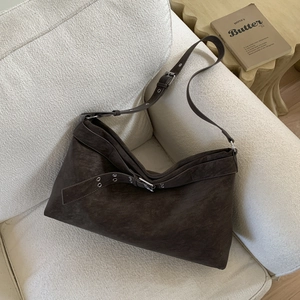 Close-up of vintage dark brown faux suede tote bag with metal buckle on a cozy sofa