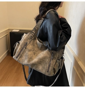 Detail view of large taupe retro tote bag showing textured soft leather and side pockets
