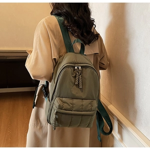 Detail of army green quilted backpack with woven zipper pulls and fashion logo straps