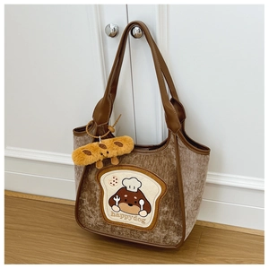 Close-up of brown corduroy tote bag with cartoon dog patch and plush biscuit charm