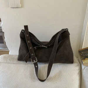 Detail of vintage brown suede tote bag featuring adjustable strap with metal buckle and holes