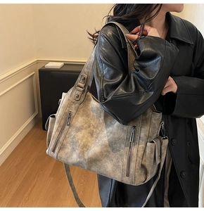 Close-up of a vintage grey soft leather tote bag with vertical decorative zippers