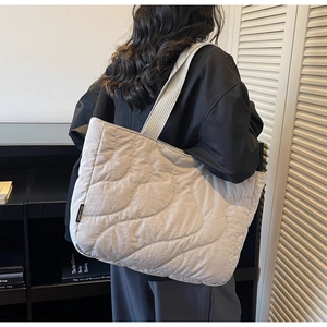 Detail of light grey quilted puffer tote bag with ribbed shoulder strap and wavy stitching