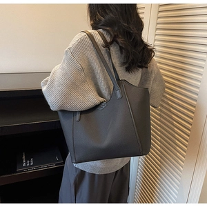 Detail of dark grey litchi grain leather tote bag showing spacious design and shoulder strap