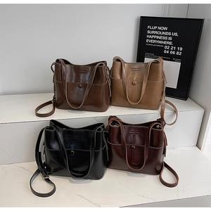 Close-up of four colors of faux leather bucket bags with adjustable shoulder straps