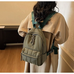Detail of olive green quilted backpack with woven straps and dual zipper closure