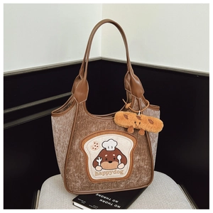 Detailed close-up of brown plush tote bag with cartoon dog embroidery and soft charm