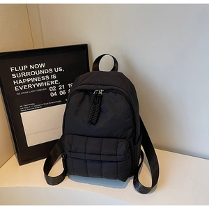 Macro view of black quilted nylon backpack featuring puffy grid pattern and durable zippers