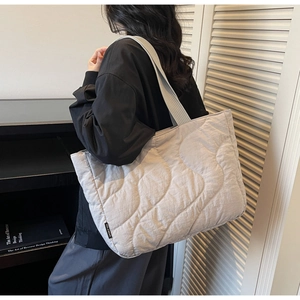 Detailed back view of a light gray quilted tote bag with wave stitching and web handle