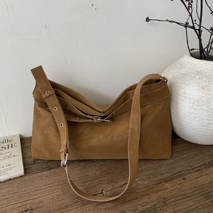Detail view of brown faux suede hobo bag with adjustable silver eyelet strap