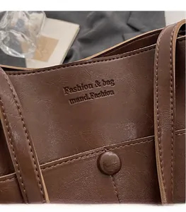 Detail of dark brown leather bucket bag showing fine stitching and embossed logo