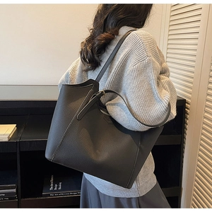Detail of black lychee grain leather tote bag with shoulder strap and metal buckle