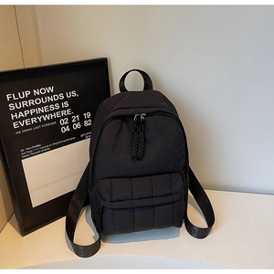 Detail of black quilted nylon backpack featuring durable zipper and branded strap