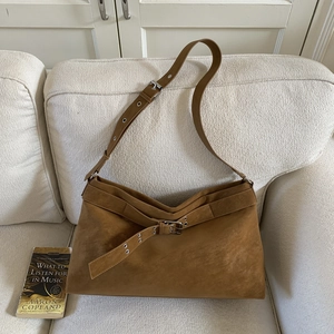Macro shot of brown suede tote bag with belt buckle detail and soft texture on a sofa