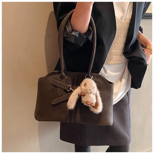 Detail of dark grey suede tote bag with decorative buckle and plush rabbit charm
