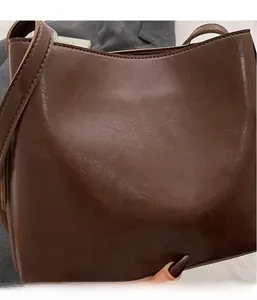 Close-up of soft dark brown PU leather bucket bag with vintage textured surface detail