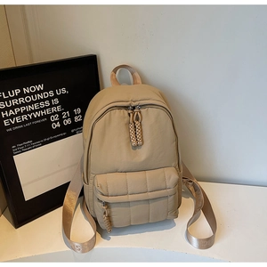 Detail of khaki quilted nylon backpack with zip pocket and woven letter straps