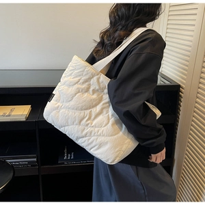 Detail of white quilted nylon tote bag with wave stitching and side brand label