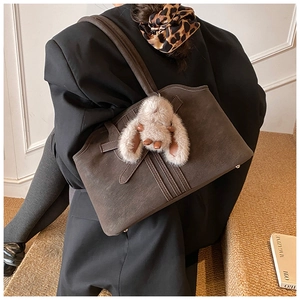 Detail of dark brown suede tote bag with vertical stitching and fluffy rabbit charm