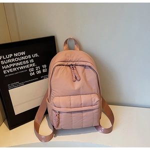 Detail of dusty pink quilted nylon backpack with padded texture and decorative straps