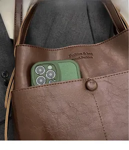 Detail of brown faux leather shoulder bag with lychee texture and phone storage pocket