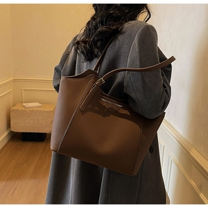 Detail of large brown tote bag showing premium lychee grain leather and fashion brand print