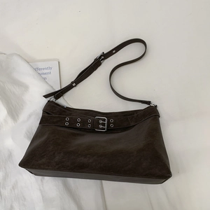 Macro detail of dark brown tote bag featuring silver eyelet strap and matte leather texture