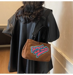 Vue arrière d'un mannequin portant le sac bandoulière en daim marron avec broderie