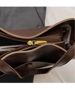 Close-up of golden zipper hardware and interior lining of dark brown bucket bag