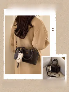 Détail du sac Boston en cuir marron foncé avec logo doré et breloque chien en peluche