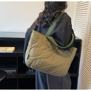 Quilted olive green tote bag with wave stitching and wide shoulder strap on model