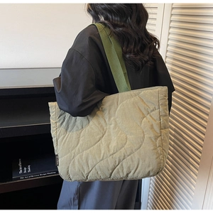 Detailed S-wave quilted pattern and brand label on a sage green tote bag for women