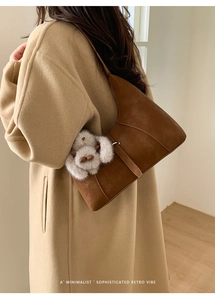 Detailed side view of a brown retro shoulder bag with a white plush bunny charm pendant