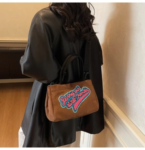 Détail du sac à main en peluche marron avec broderie Jerry et bandoulière amovible