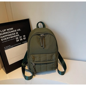 Detail of army green quilted nylon backpack with textured front pocket and woven puller