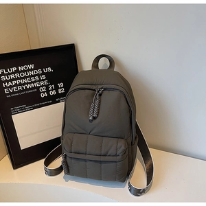 Detail of dark grey-green quilted backpack with woven rope zipper and padded texture