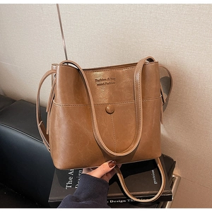 Détail du sac seau en cuir PU marron avec texte embossé et bandoulière réglable