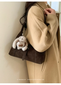 Detail of dark brown suede crossbody bag with vintage strap and plush rabbit charm