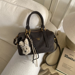 Détail du sac Boston en cuir marron foncé avec ferrures dorées et breloque lapin blanc