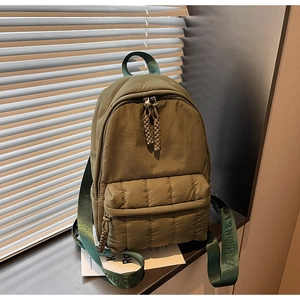 Detailed close-up of olive green quilted backpack featuring fashion & love strap letterings