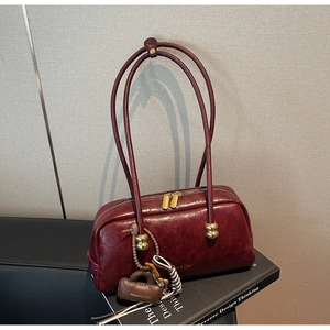 Detalle de bolso de hombro en cuero vintage burdeos con herrajes dorados y logotipo