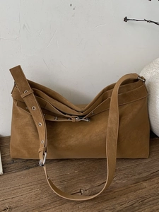 Retro tan suede tote bag with adjustable grommet strap on a vintage wooden table