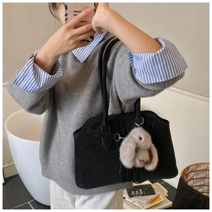 Detail of black suede tote bag with vertical stripes and a cute grey bunny plush charm