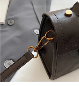 Détail du crochet en métal bronze vintage sur un sac à main en cuir marron foncé haut de gamme